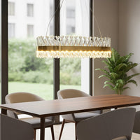 Gold metal chandelier with clear crystal rods glowing warmly above a modern dining table creating a luxurious bright and elegant interior setting.