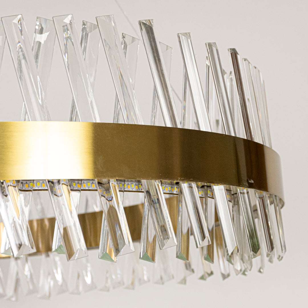 Closeup of gold metal chandelier highlighting the faceted crystal rods and polished gold ring frame designed for premium elegant interior lighting.