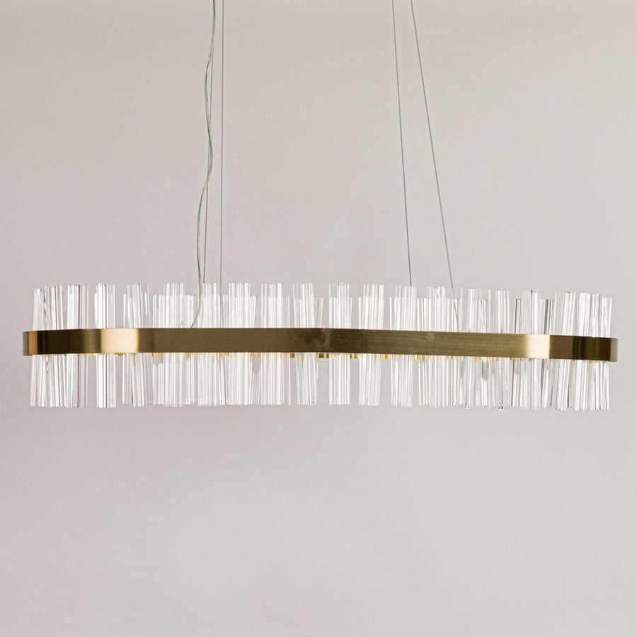 Gold metal chandelier with clear crystal rods displayed with lights off on a clean white background showcasing its sleek elongated shape.
