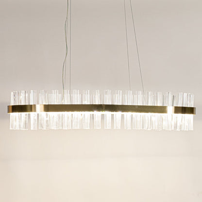 Gold metal chandelier with crystal rods shown with lights on creating a warm luxurious glow for modern interior spaces.