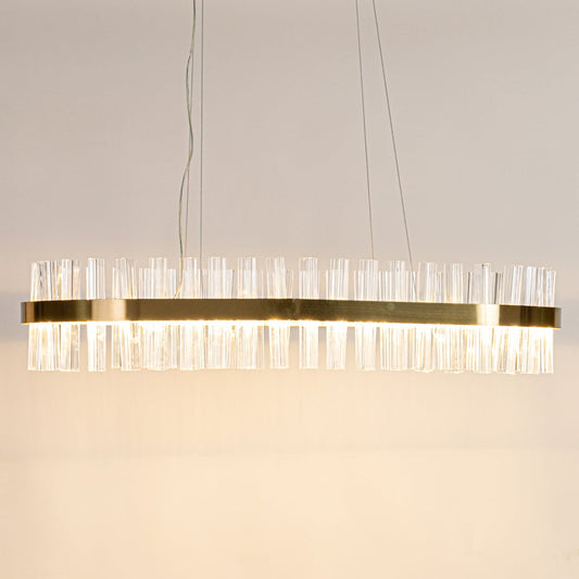 Gold metal chandelier with clear crystal rods displayed with lights on highlighting its sleek modern elongated frame.