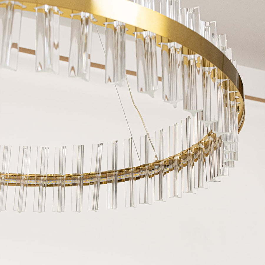 Closeup of gold metal chandelier highlighting the clear crystal rods and elegant ring frame designed for premium modern interior lighting.