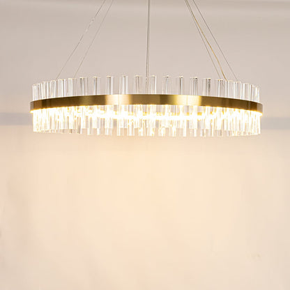 Gold metal chandelier with crystal rods shown with lights on creating a warm elegant and sparkling lighting effect.