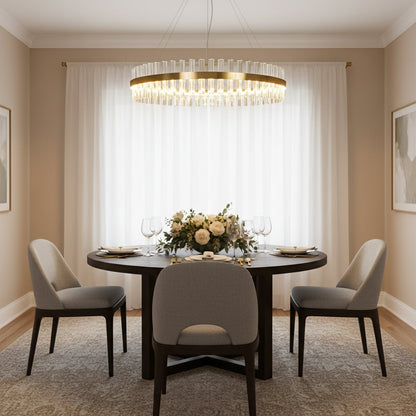 Gold metal chandelier with clear crystal rods glowing above a round dining table creating an elegant luxurious and softly lit modern interior atmosphere.