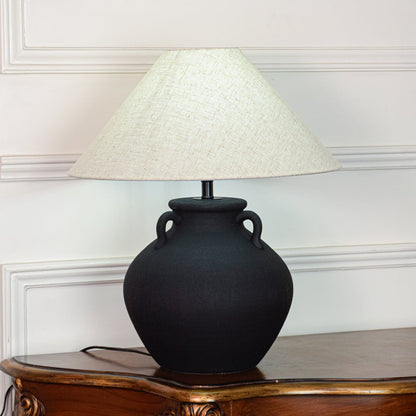 Black ceramic table lamp featuring textured matte finish rounded pot base and wide fabric shade displayed on white background.