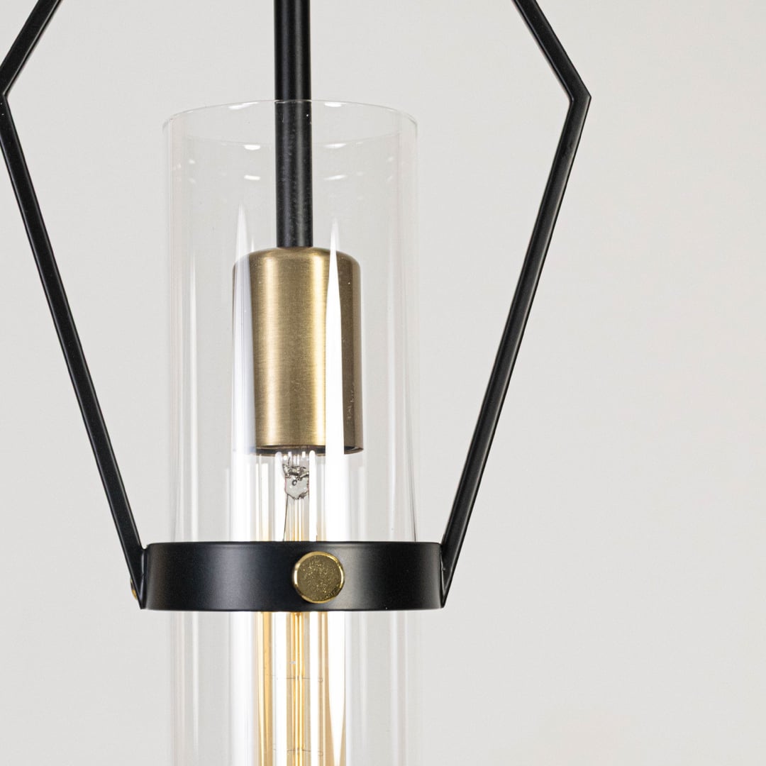 Closeup of black and gold geometric pendant light showing clear glass shade and refined metal detailing.