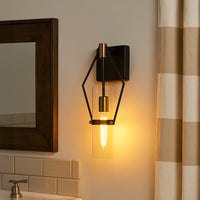 Modern black metal wall sconce with gold accents and clear glass shade adding warm ambient lighting to a stylish interior.