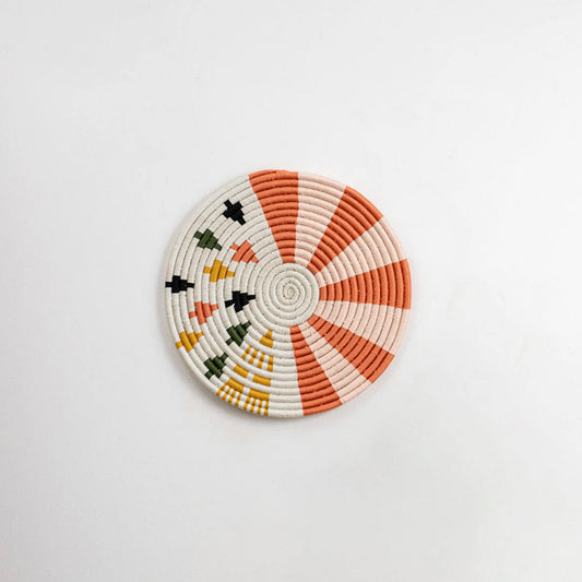 Round handcrafted seagrass wall basket with coral orange cream and black pattern on white background image.