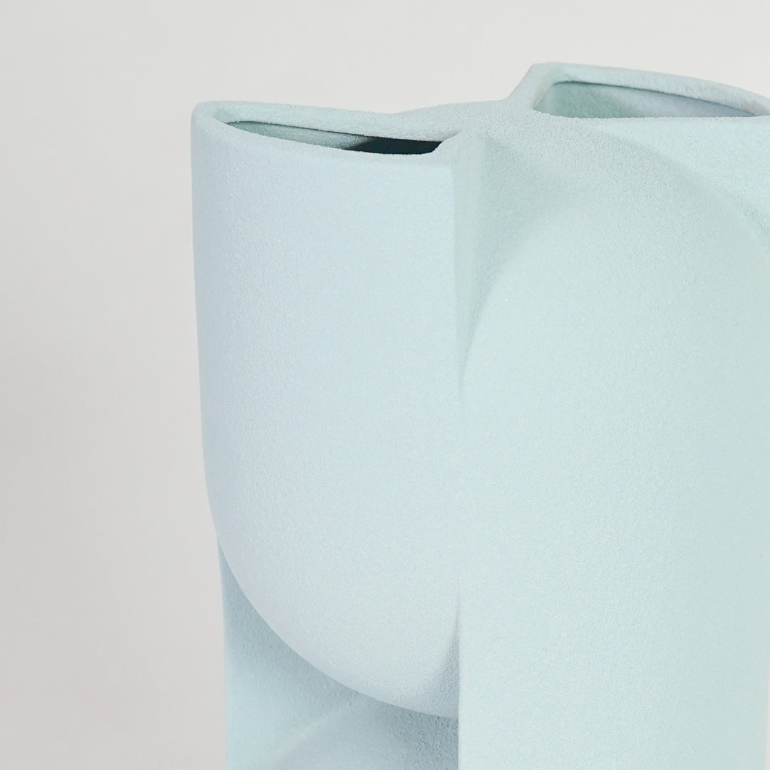Closeup image of light blue ceramic abstract vase for modern tabletop decor styling with smooth matte finish.