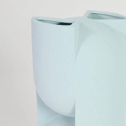 Closeup image of light blue ceramic abstract vase for modern tabletop decor styling with smooth matte finish.