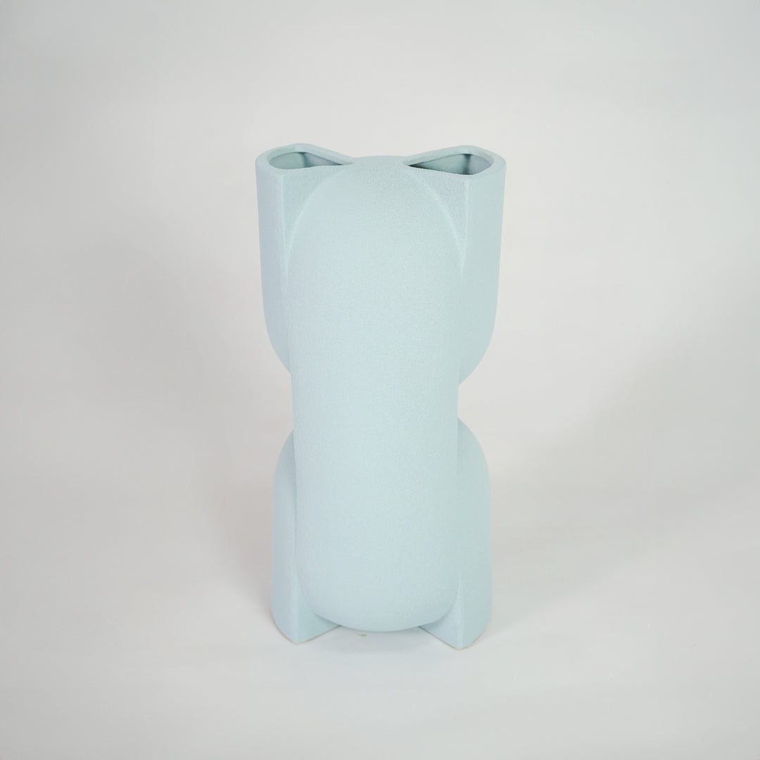 Light blue ceramic vase for modern shelf placement and elegant indoor home decor styling accent piece.