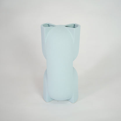 Light blue ceramic vase for modern shelf placement and elegant indoor home decor styling accent piece.