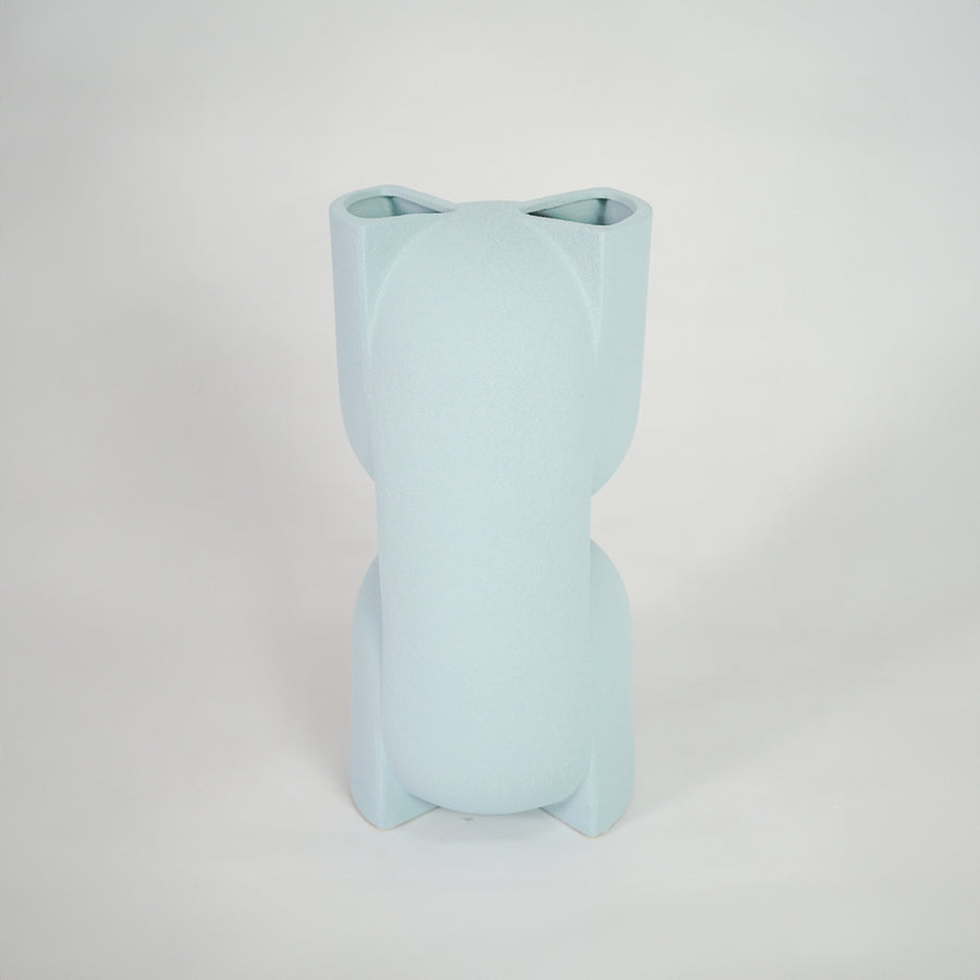 Light blue ceramic vase for modern shelf placement and elegant indoor home decor styling accent piece.