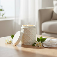 White ceramic decorative jar with lid placed on table creating clean and elegant living space decor accent.