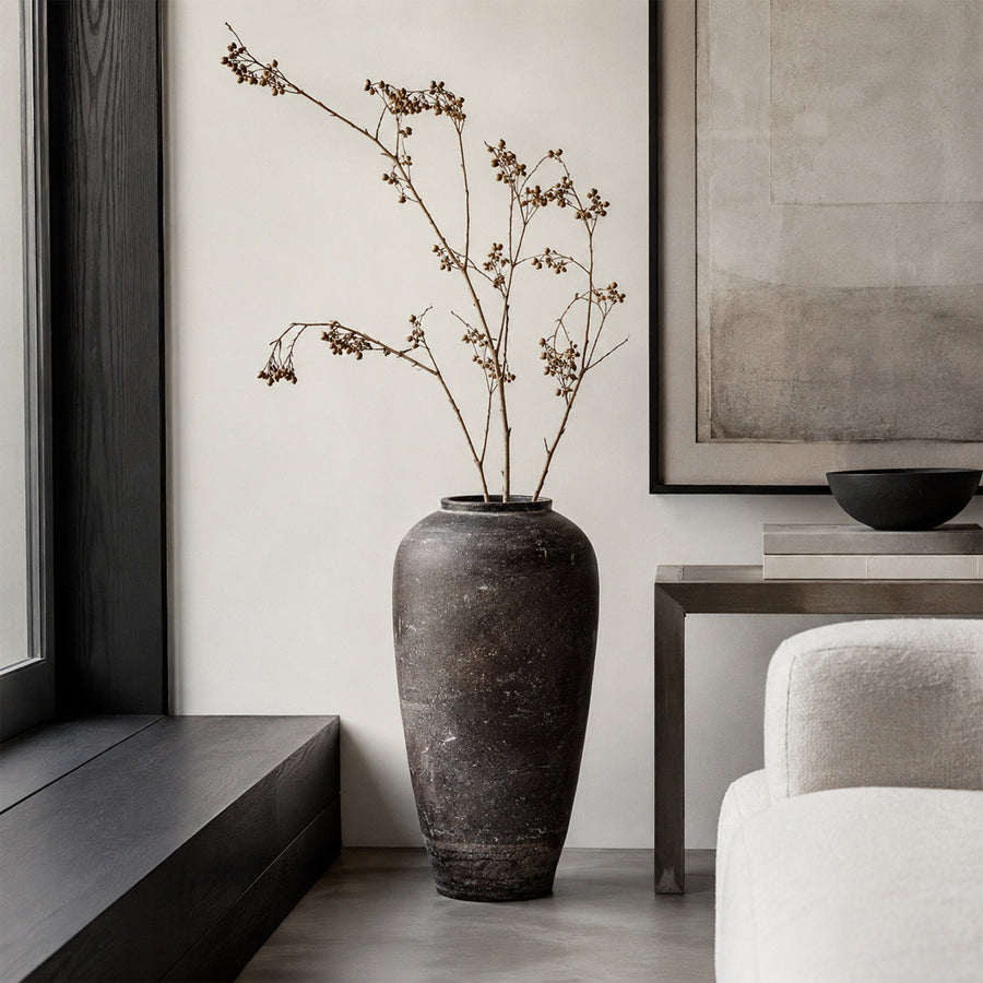 Dark brown textured floor vase placed beside chair for elegant modern home decor styling.