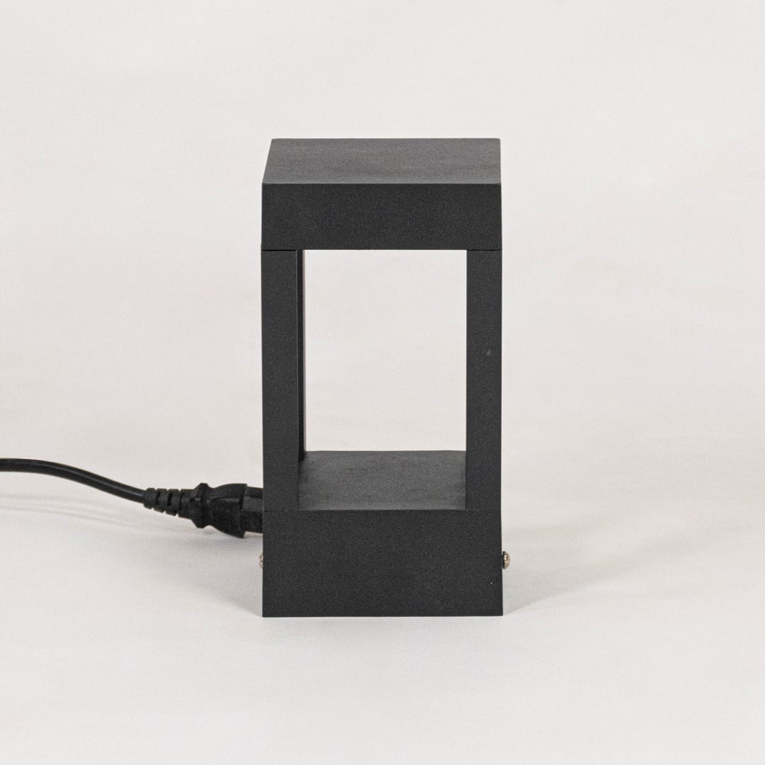 Minimal black pillar light with matte metal frame displayed off on plain white background surface.
