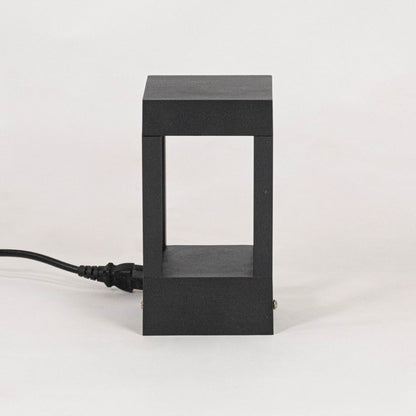 Minimal black pillar light with matte metal frame displayed off on plain white background surface.
