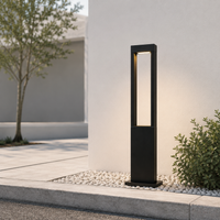 Modern black metal rectangular hollow bollard post light on white pebble path for minimalist home backyard landscape decor.