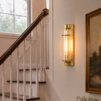 Luxury gold brass long glass cylinder tube wall sconce fixture mounted beautifully on a transitional staircase wall.