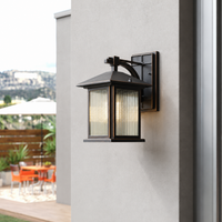 Modern black aluminum rectangular frosted glass wall lantern on white stucco facade for outdoor house patio lighting.