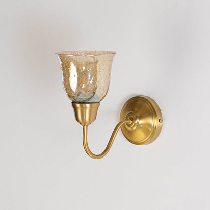 Elegant brass wall sconce with amber glass shade in off position displayed on clean minimal white background product view.