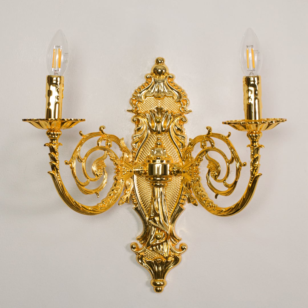 Closeup of gold wall light showing sculpted metal details and candle style bulbs for premium elegant interior lighting.