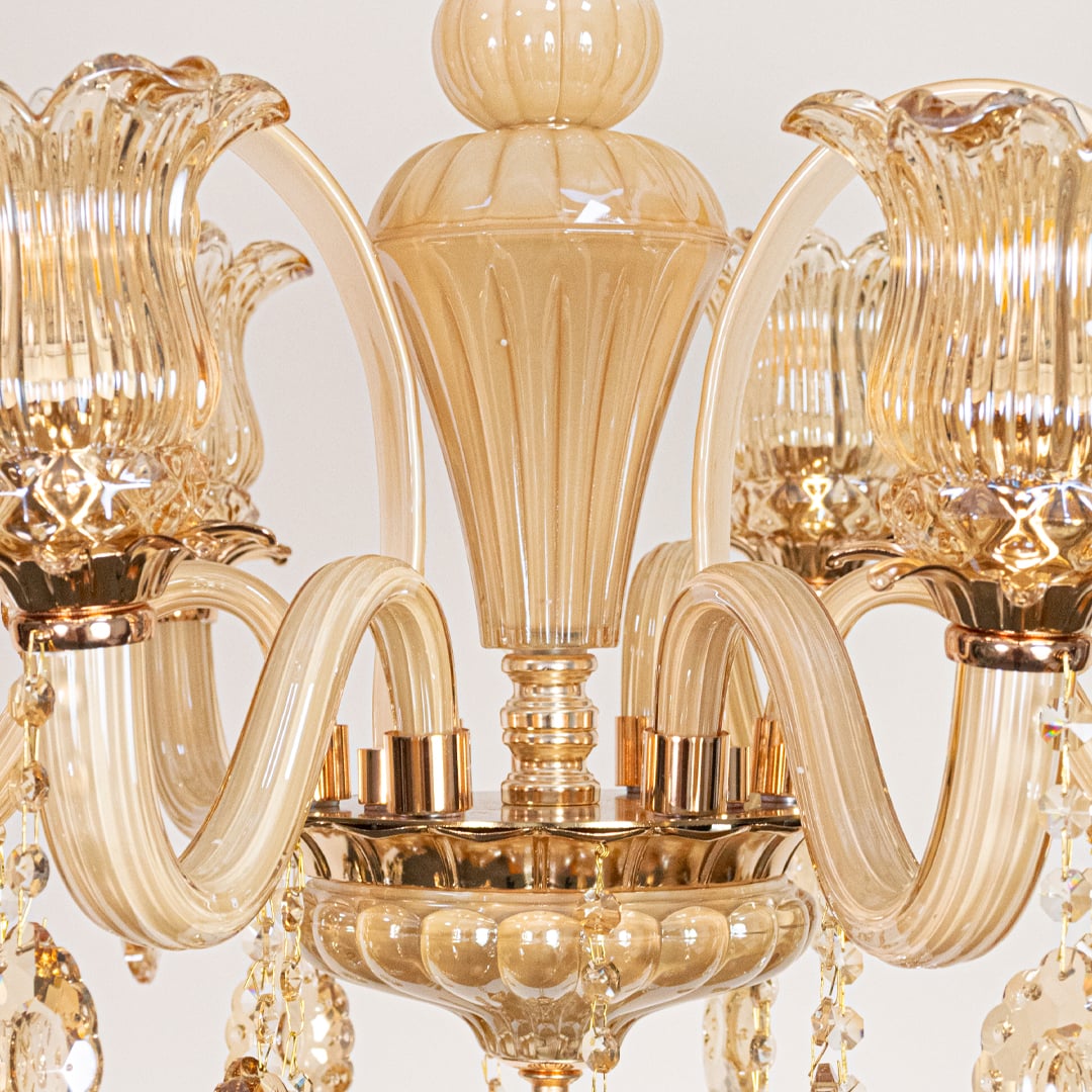 Closeup of golden glass crystal chandelier with detailed curves and beads perfect for luxury interior ceiling lighting.