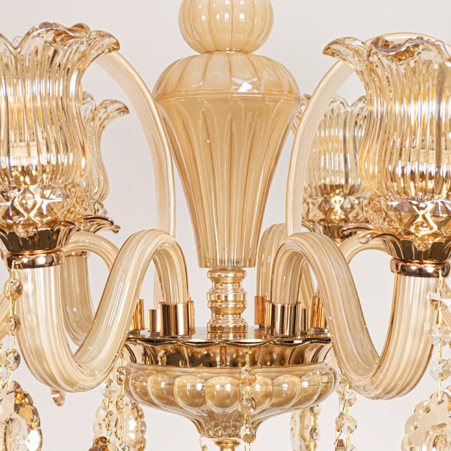 Closeup of golden glass crystal chandelier with detailed curves and beads perfect for luxury interior ceiling lighting.