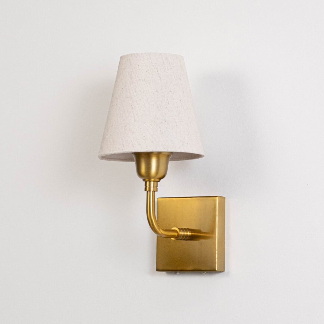 Gold metal wall mounted light switched off on white background emphasizing clean lines and timeless design.