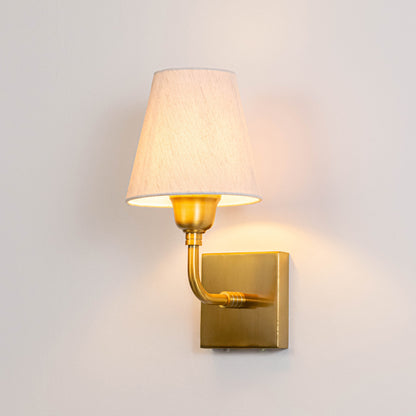 Elegant metal wall light in gold finish with fabric shade for bedside or living room ambient lighting decor placement white background.