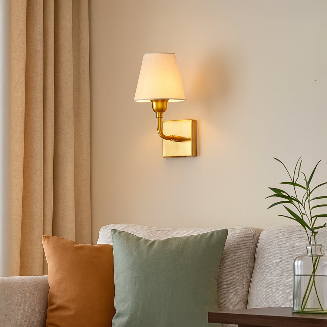 Gold metal wall light with beige fabric shade mounted beside bed adding soft ambient lighting to elegant bedroom Decor.