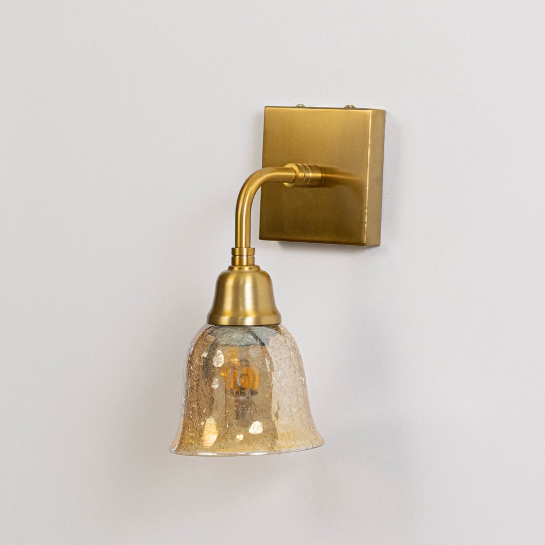 Gold metal wall mounted light switched off on white background emphasizing curved arm glass shade and elegant finish.
