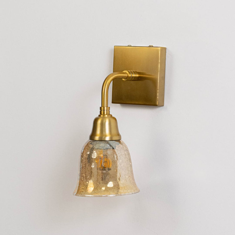 Gold metal wall mounted light switched off on white background emphasizing curved arm glass shade and elegant finish.