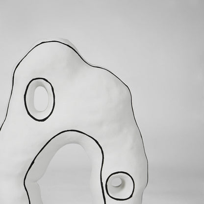 Detailed view of organic sculptural curves and black accent outline on white ceramic vase for artistic home decor.
