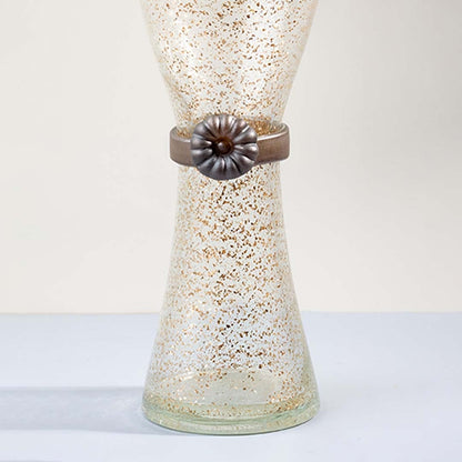 Closeup of tall golden speckled glass vase with metallic floral accent detail showing elegant craftsmanship for decor.