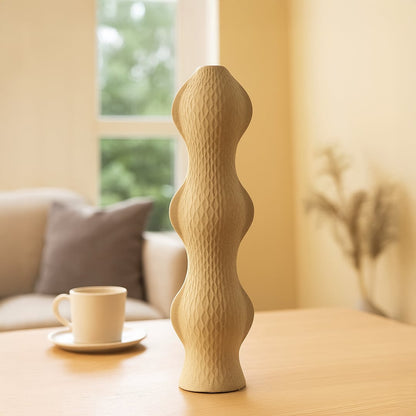 Stylish beige ceramic vase with sculptural wavy design placed on wooden table enhancing living room decor with minimal modern charm.