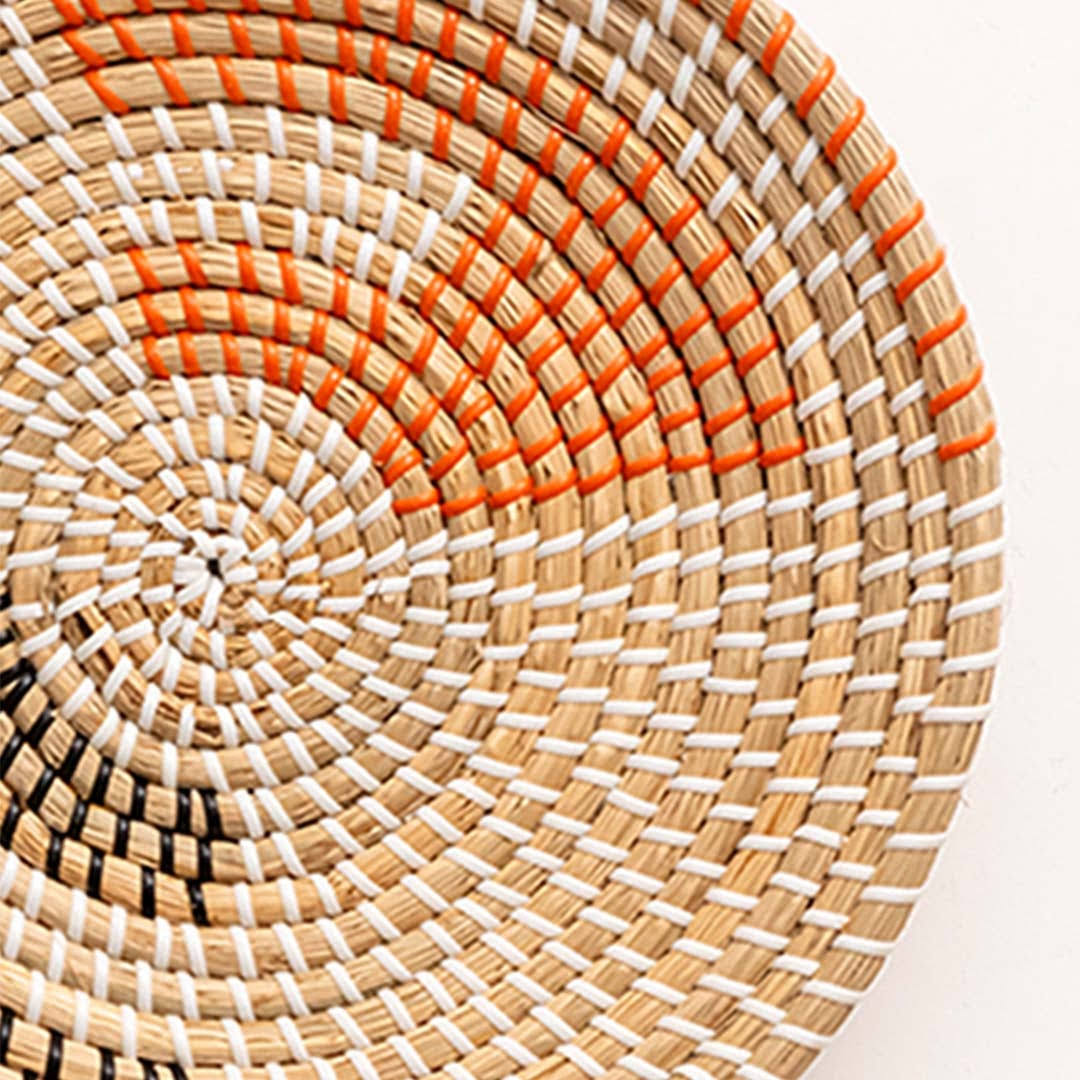 Closeup of handwoven natural seagrass basket showing detailed orange black and natural woven texture for boho home decor.