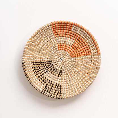 Handwoven seagrass wall basket with orange and black pattern for living room bedroom and entryway decor on white background.