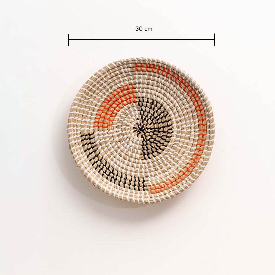 Round woven wall basket in natural and orange tones showing approx 30 cm diameter for accurate wall decor placement.