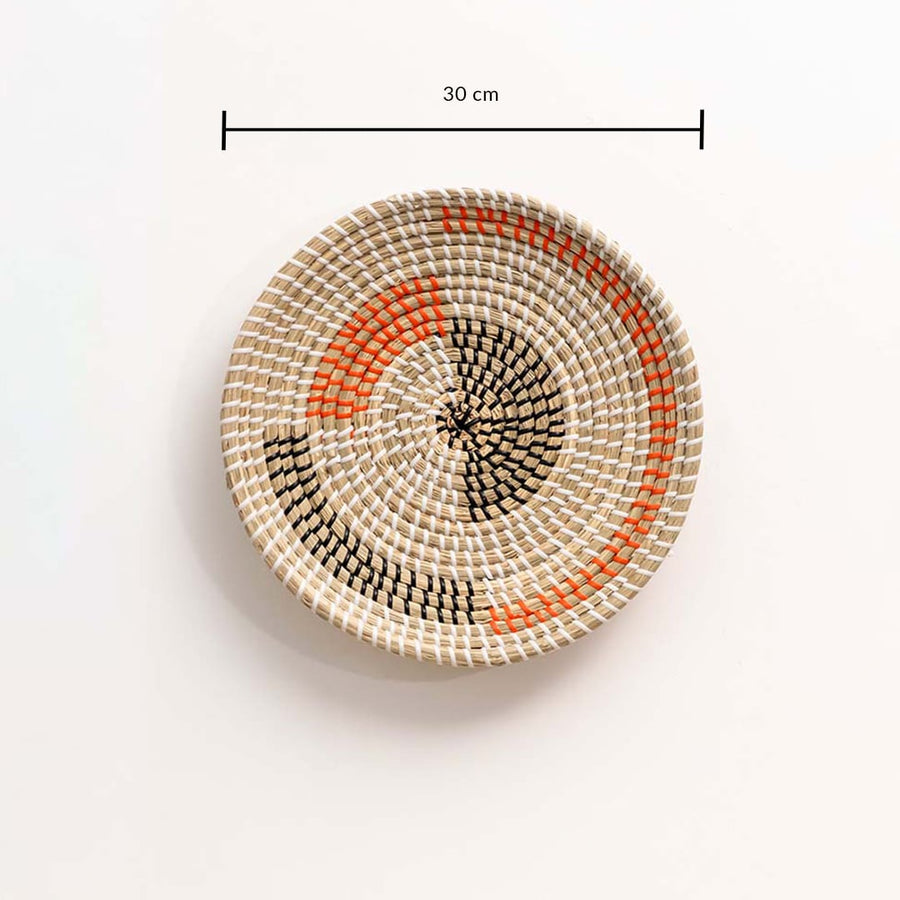 Round woven wall basket in natural and orange tones showing approx 30 cm diameter for accurate wall decor placement.