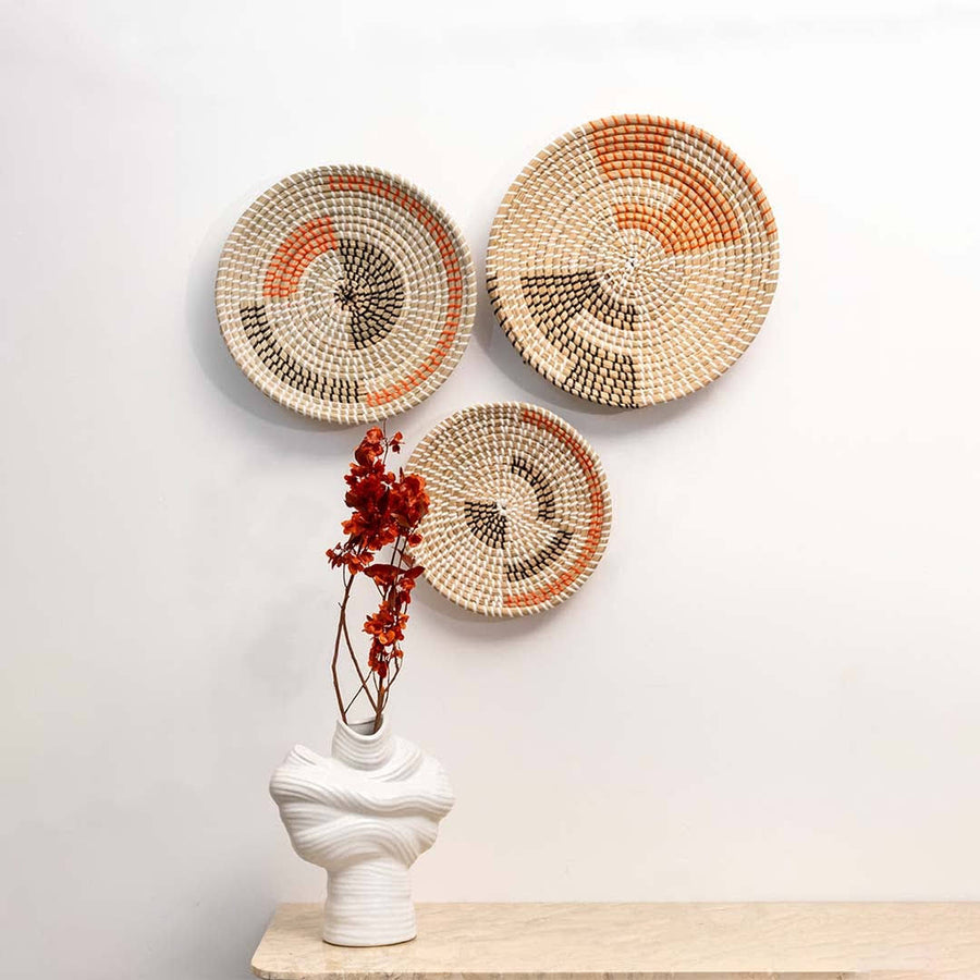 Trio of boho woven baskets wall-mounted above a minimalist marble console with a sleek white vase and dried botanical accents.