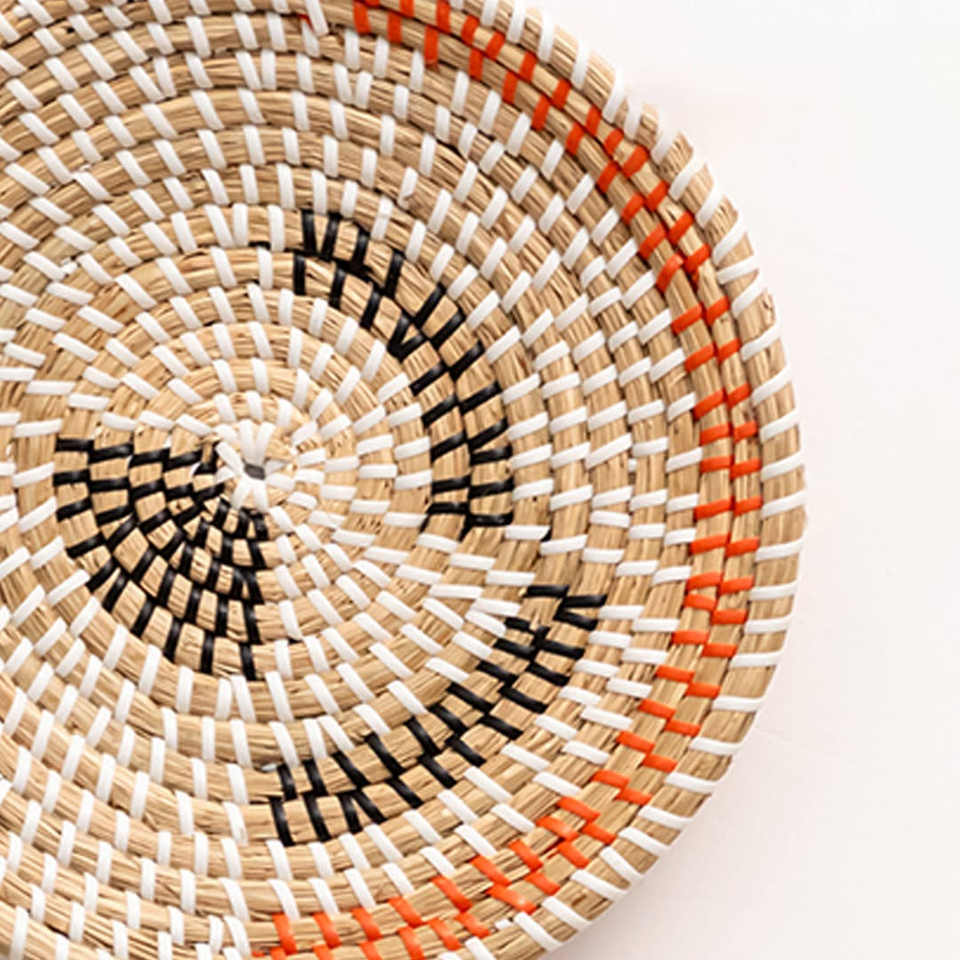 Closeup of handwoven seagrass wall basket showing intricate black and rust woven weave texture for living room wall art.