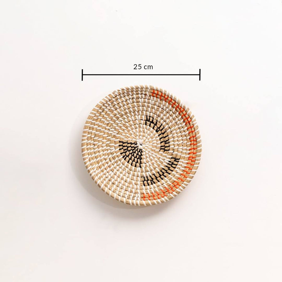 Handwoven seagrass wall basket with orange and black motifs shown with a 25 inch dimension measurement for home decor.