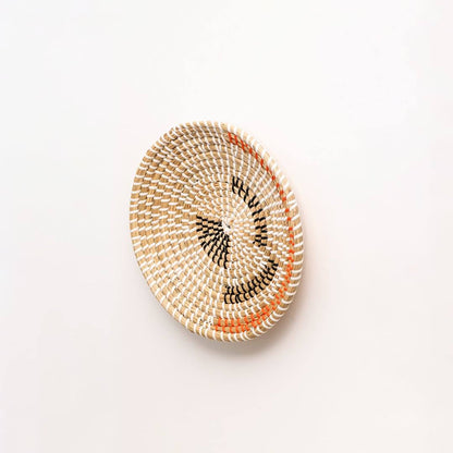 Side view of handwoven seagrass wall basket with black and terracotta stitching for entryway and bedroom wall display.