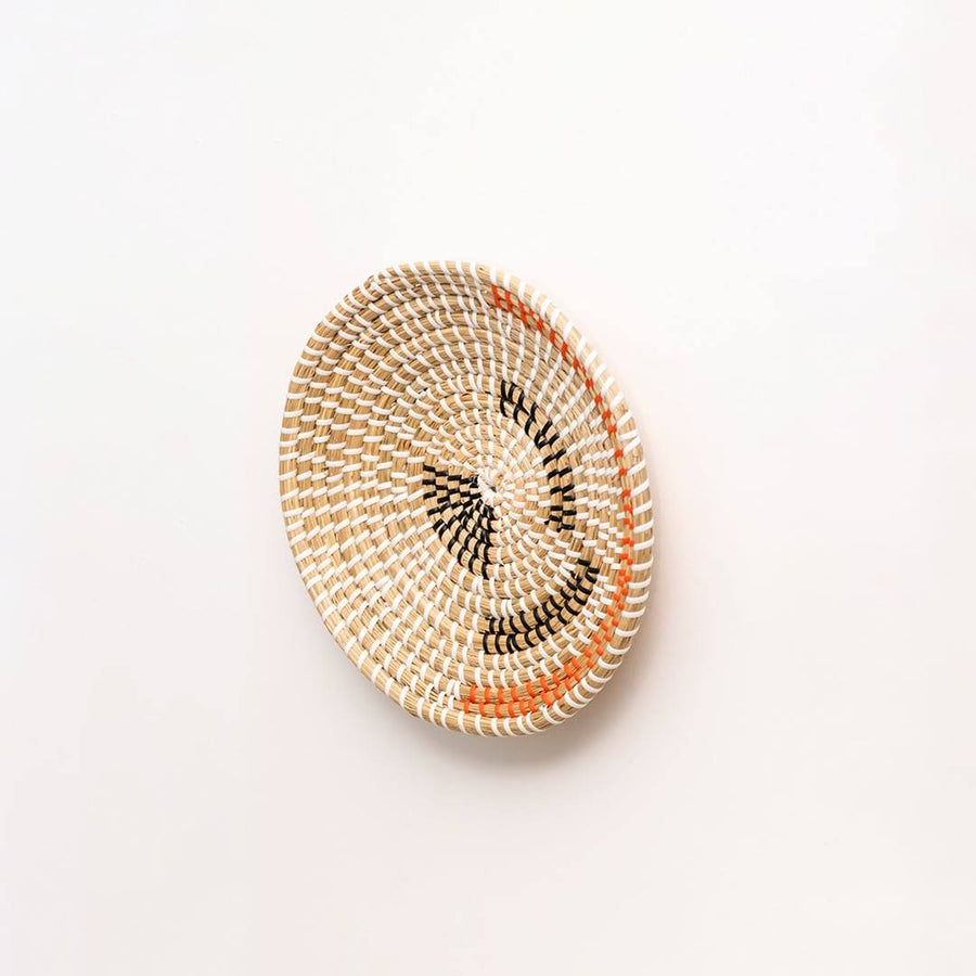 Side view of handwoven seagrass wall basket with black and terracotta stitching for entryway and bedroom wall display.