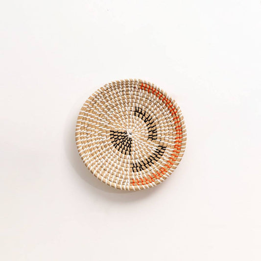 Round handwoven seagrass wall basket with black and rust patterns for bohemian living room accent on a white background.
