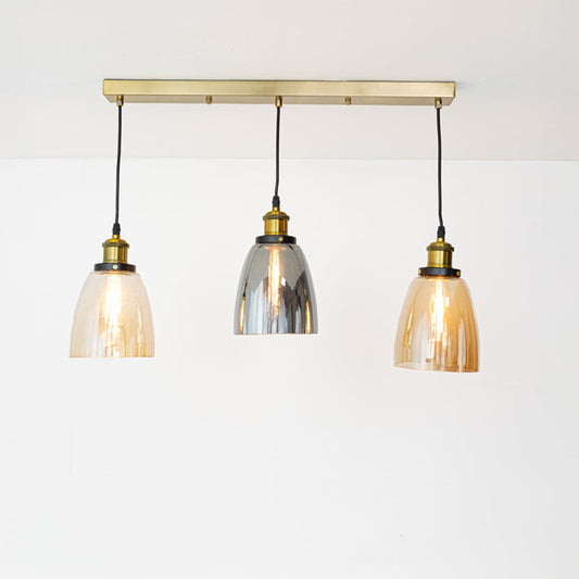 Warm glowing glass pendant trio with amber and smoked shades and gold fittings displayed on a bright white background for modern decor inspiration.