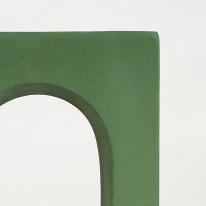 Closeup image of green retro arch table decor for elegant living room styling highlighting smooth modern painted finish.