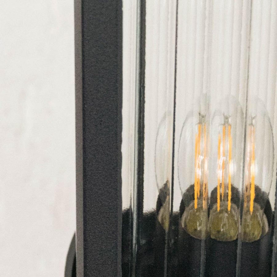 Detailed frosted glass panel of black outdoor pillar light highlighting LED filament for garden patio lighting.