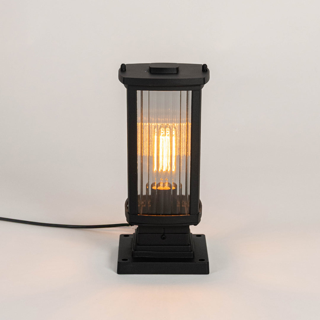 Modern black outdoor gate light with warm glowing bulb for elegant exterior decor styling use.
